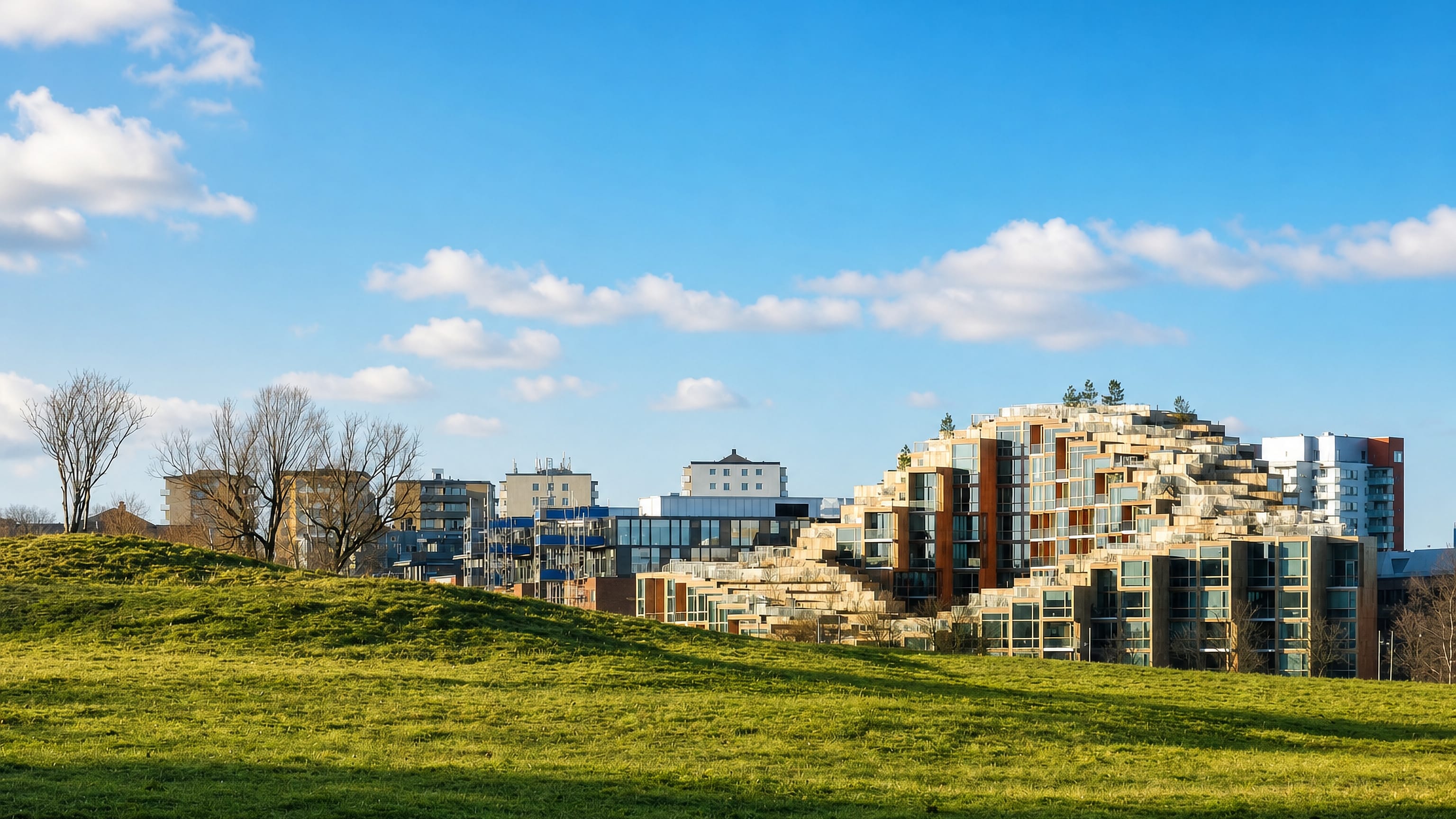 Open grass field below stepped modern apartment blocks at Ladugårdsgärdet, Stockholm.