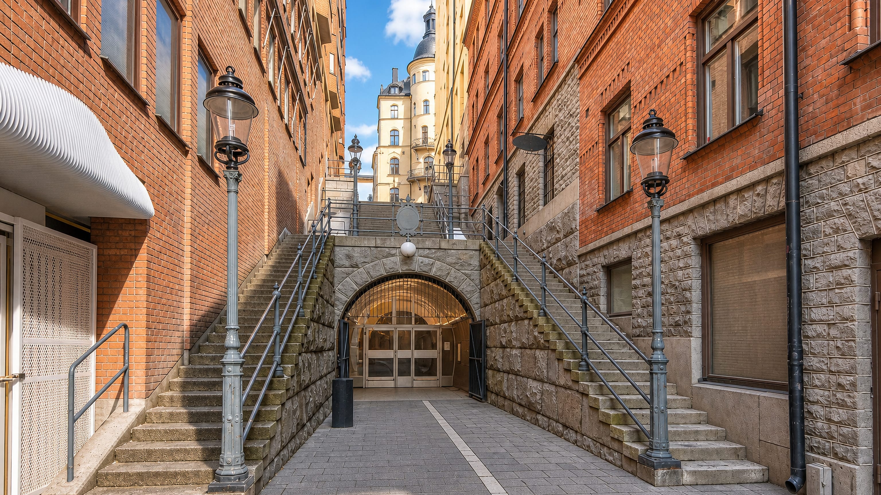 Stone staircases flanking an arched pedestrian tunnel between brick buildings in Norrmalm, Stockholm.