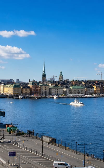 Daytime view from Södermalm across the water to Stockholm's Gamla Stan skyline of spires and pastel waterfront buildings.