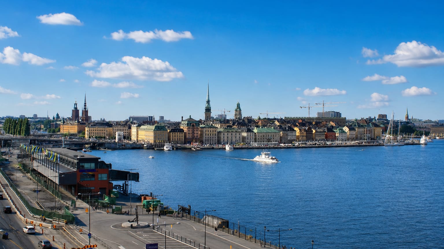 Daytime view from Södermalm across the water to Stockholm's Gamla Stan skyline of spires and pastel waterfront buildings.