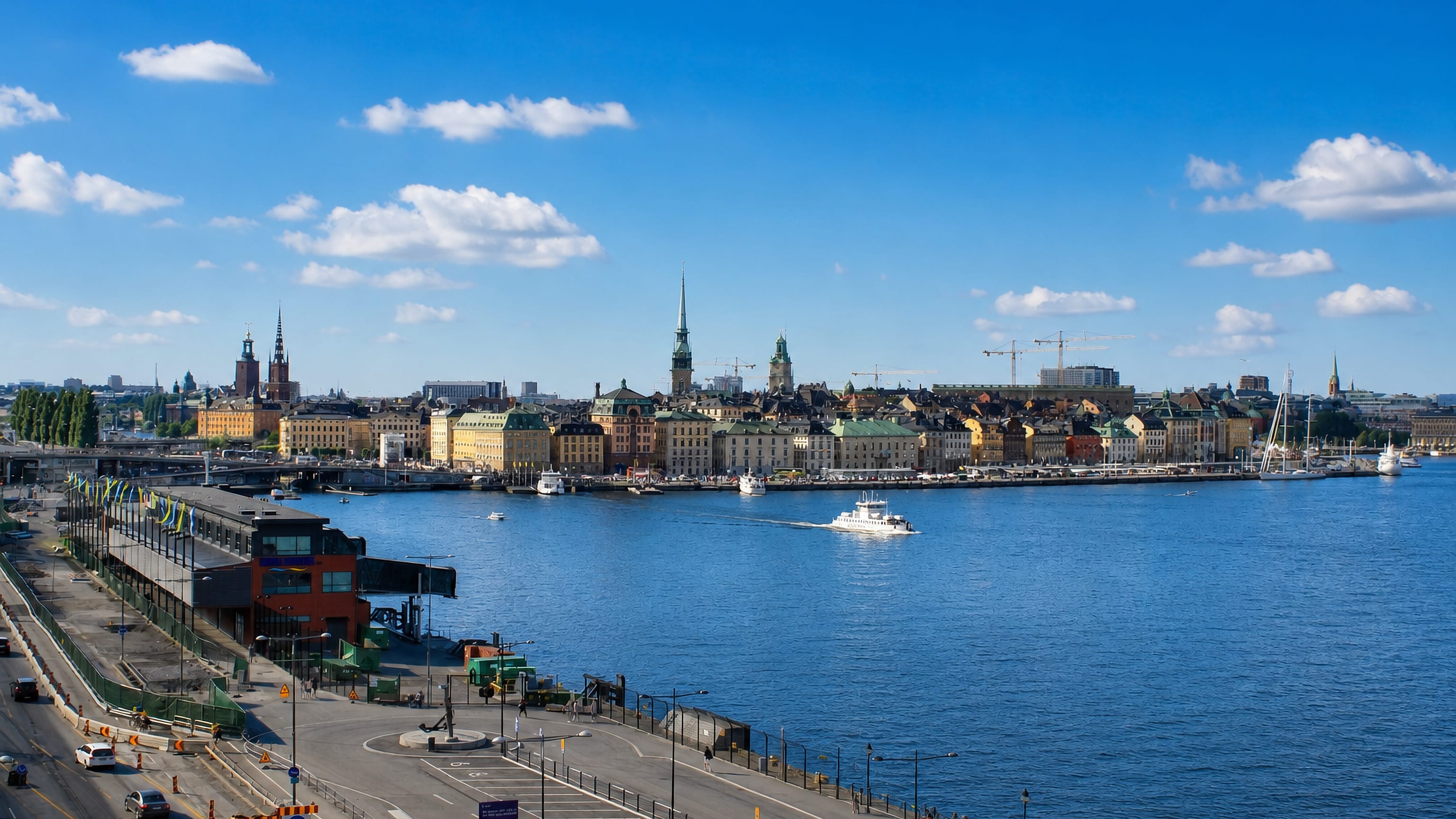Daytime view from Södermalm across the water to Stockholm's Gamla Stan skyline of spires and pastel waterfront buildings.