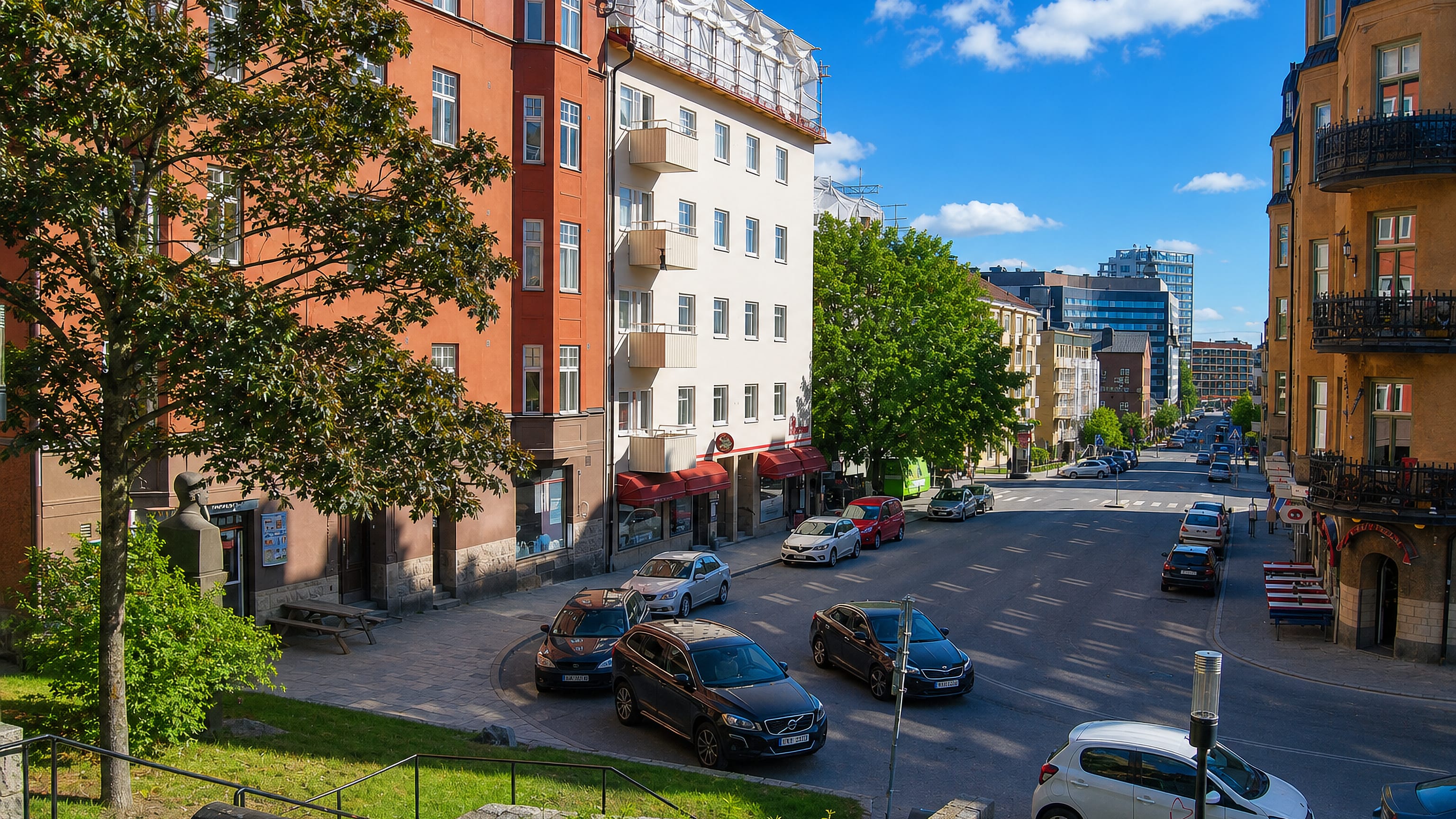 Sundbyberg street lined with red and ochre apartment blocks, parked cars and distant glass towers