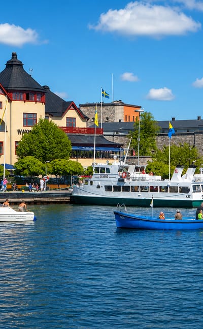 Vaxholm waterfront with the Waxholms Hotell, the round Vaxholm Fortress tower and a passenger ferry at the quay