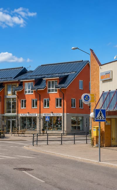 Knivsta Centrum shopping street with orange apartment blocks and shopfronts under a blue sky, Sweden.