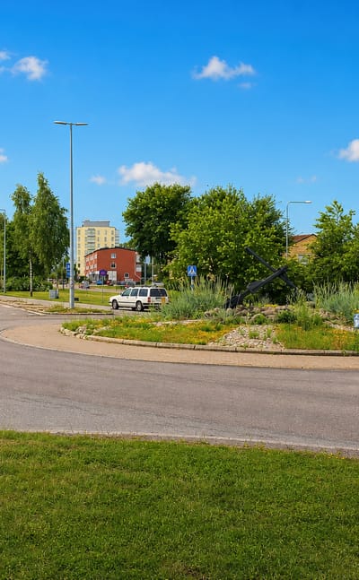 Landscaped roundabout and streets with low buildings and an apartment block in Skutskär, Uppsala County.
