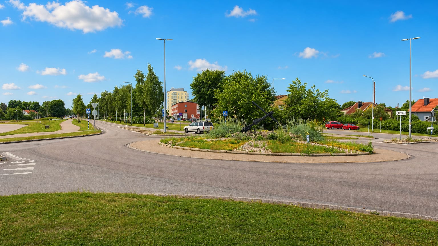 Landscaped roundabout and streets with low buildings and an apartment block in Skutskär, Uppsala County.