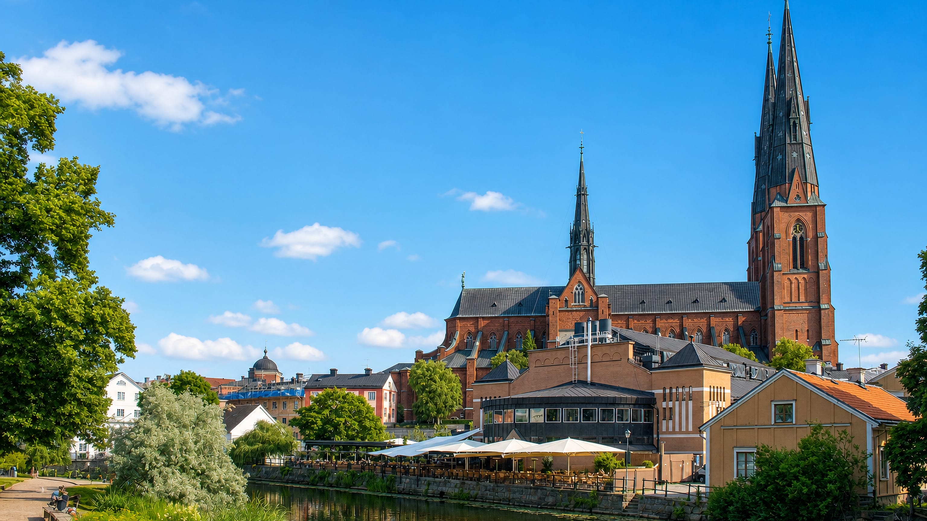 Uppsala Cathedral's twin spires rising above riverside cafés on the Fyris in Fjärdingen, Uppsala.