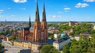 Uppsala Cathedral's twin spires above the old town with Uppsala Castle on the ridge under a blue sky