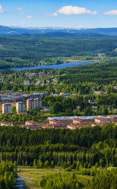 Hagfors nestled among forested hills and lakes with distant snow-capped fells in Värmland, Sweden.