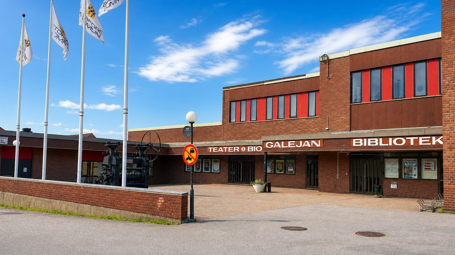The brick facade of Storfors's Galejan theatre, cinema and library with flagpoles on the town square.