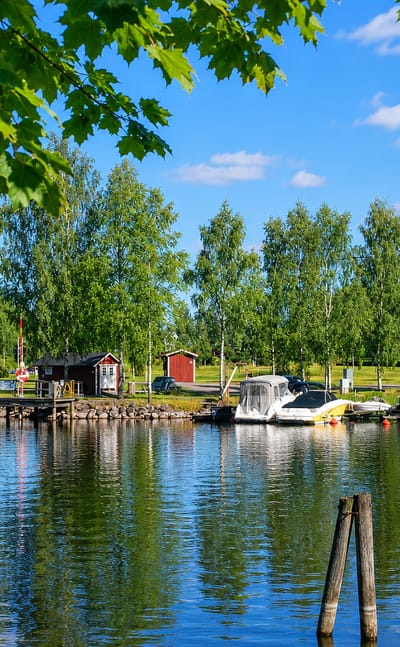 Lakeside marina with moored boats and red cabins framed by birch foliage at Sunne in Varmland, Sweden