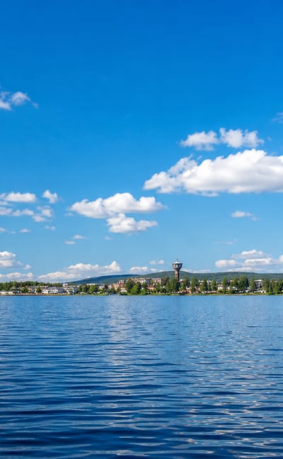 Norsjö, Sweden across the calm lake Norsjön, its church spire and low buildings under a bright blue summer sky