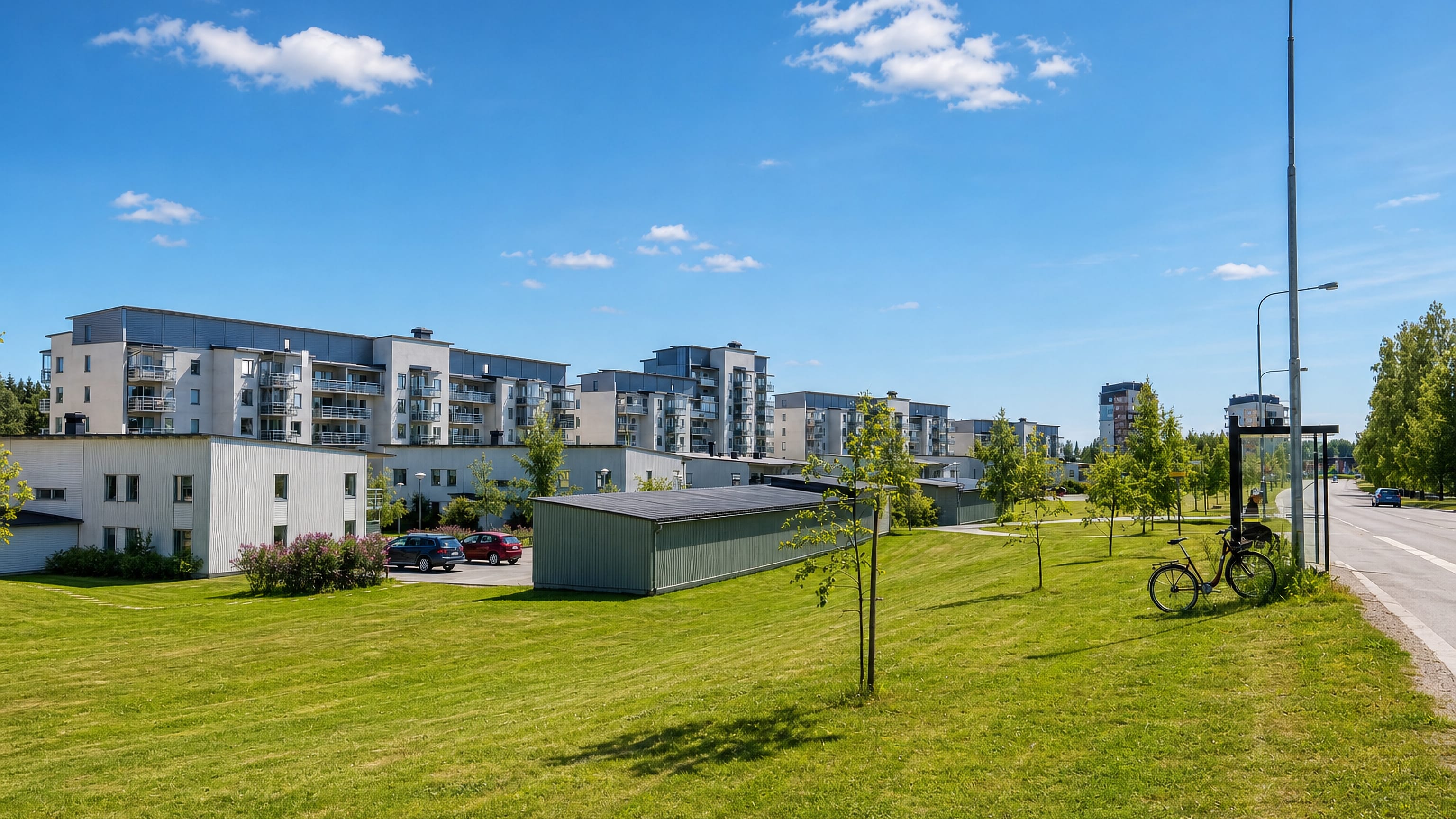 Light-toned apartment blocks and a broad mown lawn at Mariehem in Umea on a clear summer day