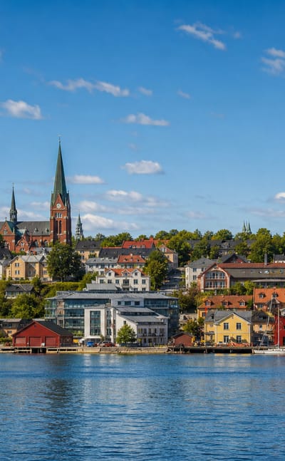 Harnosand waterfront across the water with the cathedral spire, a domed civic building and colourful harbour houses under a summer sky
