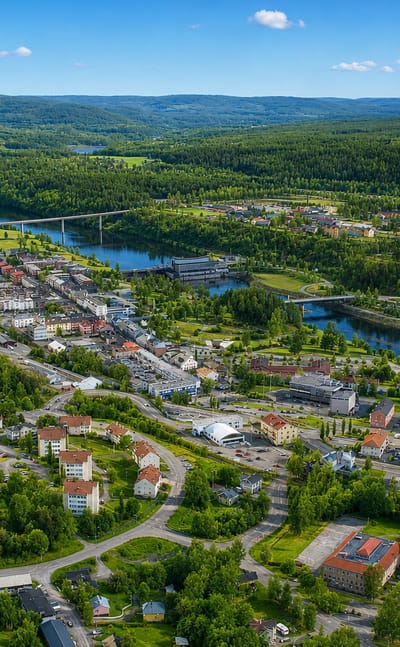 Aerial view of Sollefteaa along the Aangermanaelven river, with a bridge and forested hills in Sweden.
