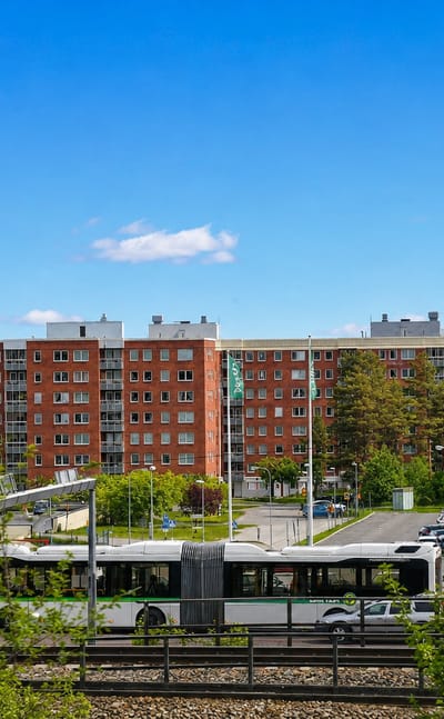 Red-brick apartment blocks, a green articulated city bus and a Tempo store in a Sundsvall neighbourhood.