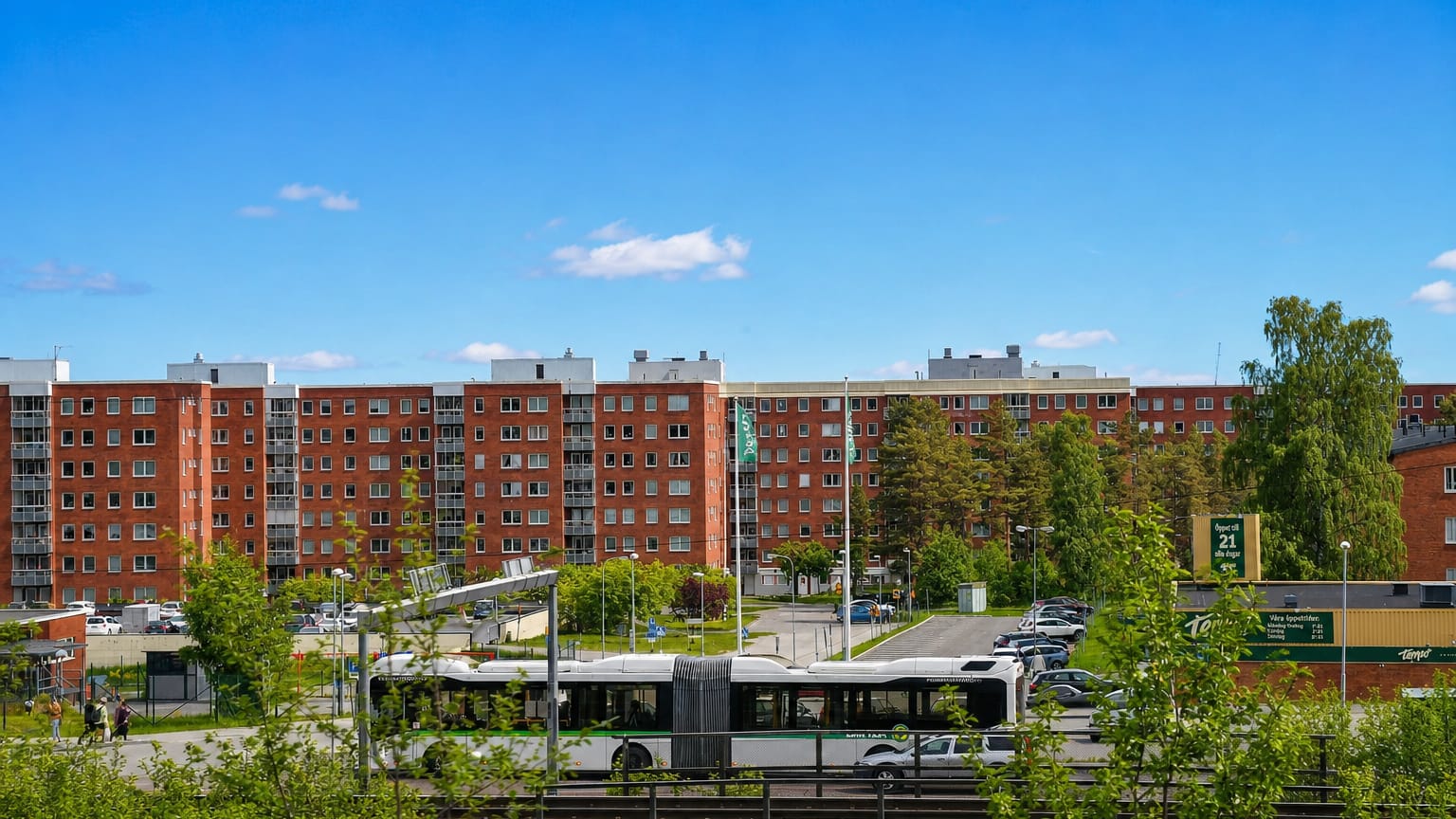 Red-brick apartment blocks, a green articulated city bus and a Tempo store in a Sundsvall neighbourhood.