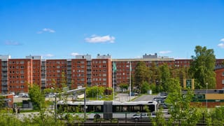 Red-brick apartment blocks, a green articulated city bus and a Tempo store in a Sundsvall neighbourhood.