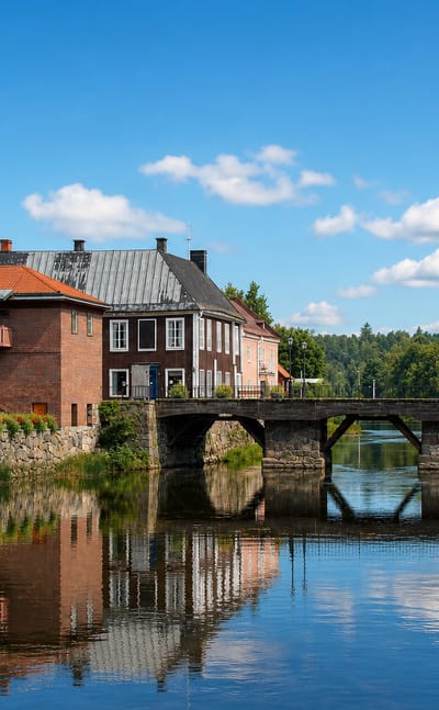 Red-brick buildings and a stone arch bridge reflected in the Arbogaan river in Arboga, Sweden.