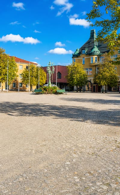 Sala's cobbled main square with its ornate yellow buildings, statue and autumn trees under a clear sky.