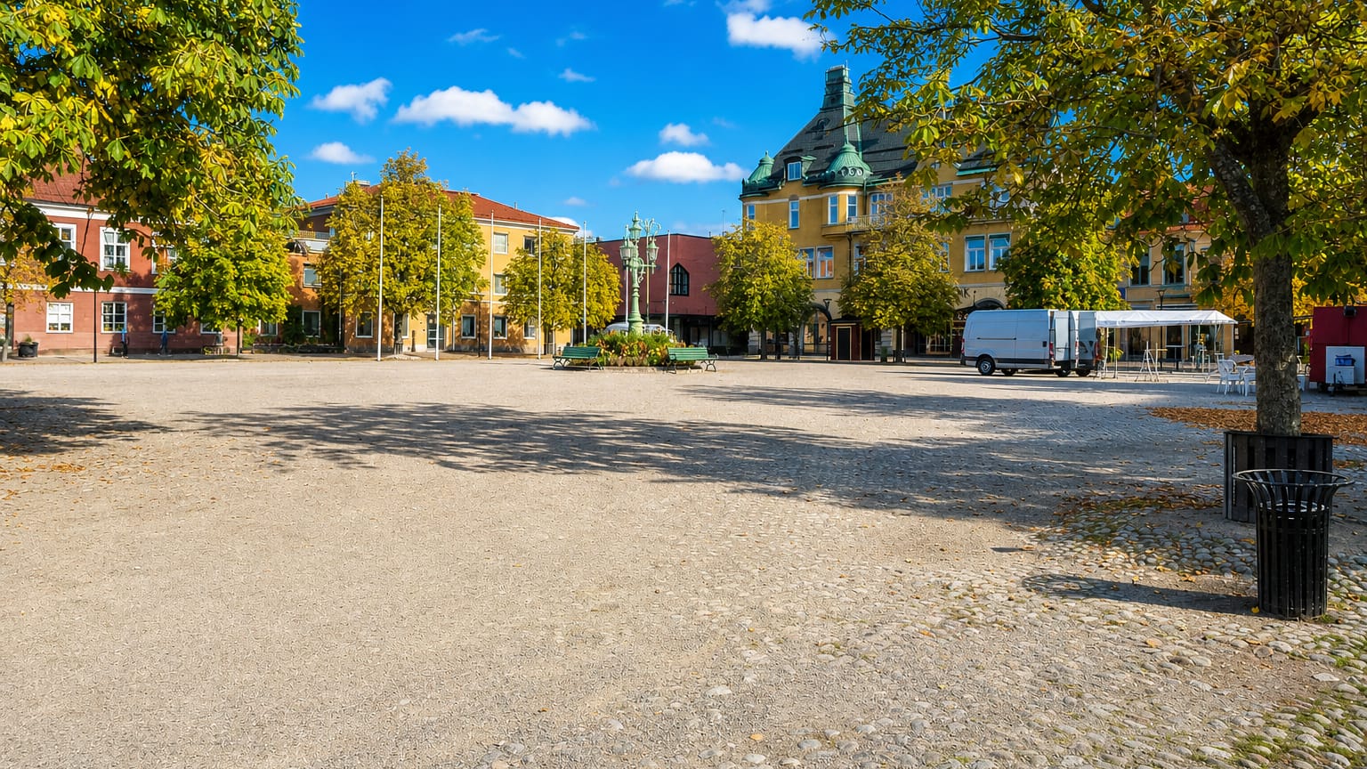 Sala's cobbled main square with its ornate yellow buildings, statue and autumn trees under a clear sky.