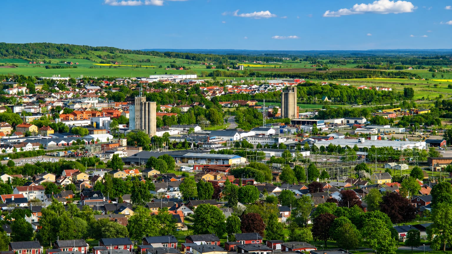 Aerial view of Falköping, Sweden with silo towers and red-roofed houses amid green farmland