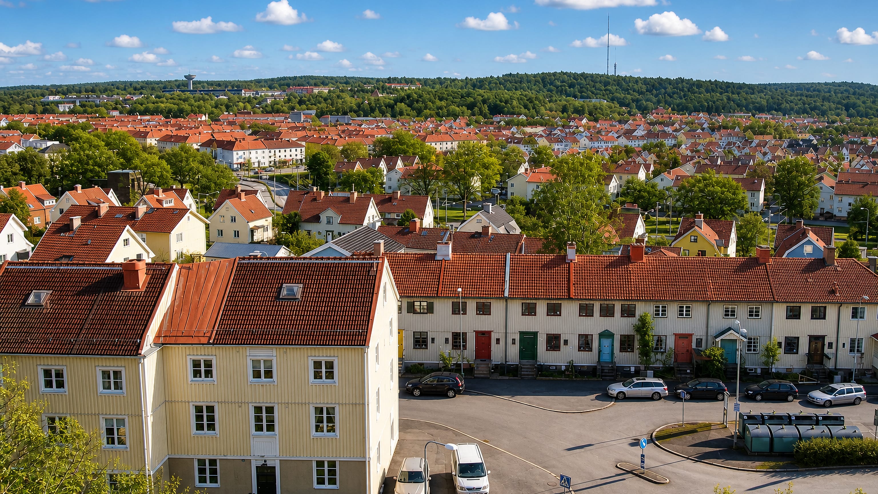 Yellow and white terraced houses with red tile roofs in Kålltorp, Gothenburg, below a wooded ridge and TV mast.