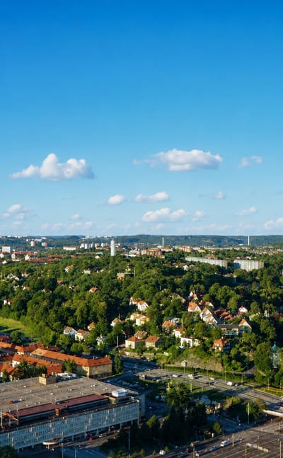 Aerial daytime view over Örgryte, a leafy residential district of eastern Gothenburg, with brick blocks, parkland and wooded hills.