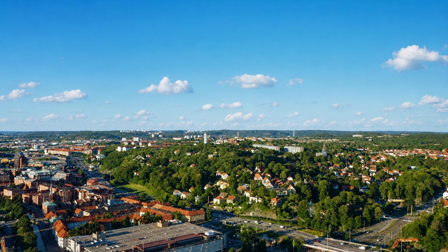 Aerial daytime view over Örgryte, a leafy residential district of eastern Gothenburg, with brick blocks, parkland and wooded hills.