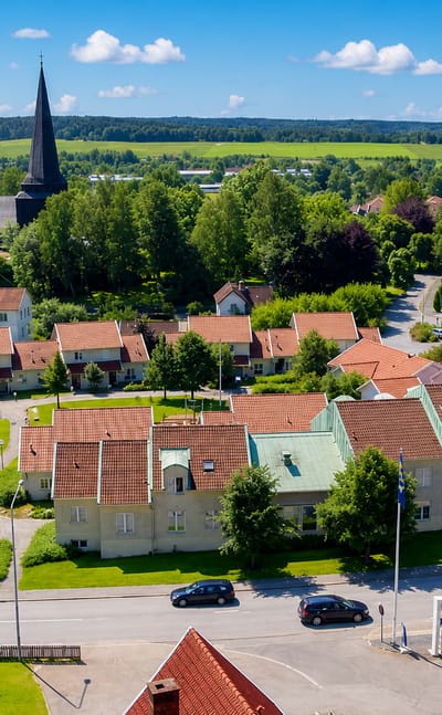 Aerial view of Kinna, Sweden, with its dark church spire, red-roofed houses and green farmland beyond.