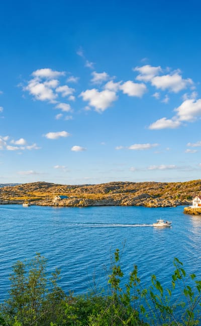 Rocky Swedish west-coast archipelago near Kungalv with blue inlets, a passing boat and scattered coastal houses