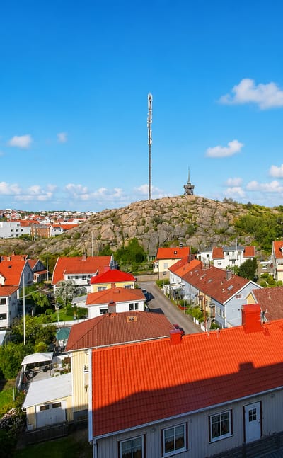 Aerial view over Lysekil's red-roofed wooden houses, granite hill and neo-Gothic church under a blue sky