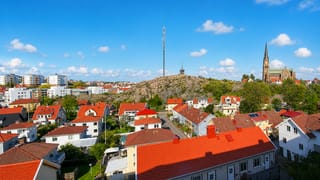 Aerial view over Lysekil's red-roofed wooden houses, granite hill and neo-Gothic church under a blue sky