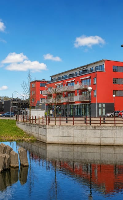 Waterside red apartment block and footbridge over a canal in Mölndal, Sweden