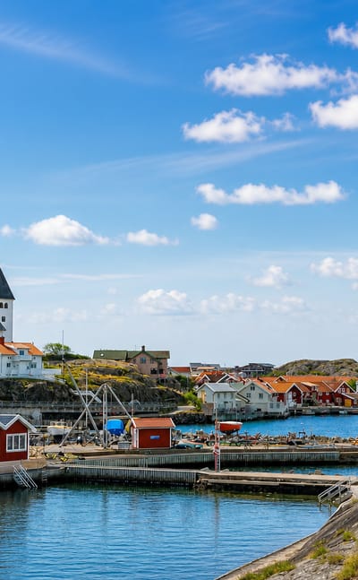 Skärhamn harbour on Tjörn with a white hilltop church, red boathouses and granite rocks by the sea
