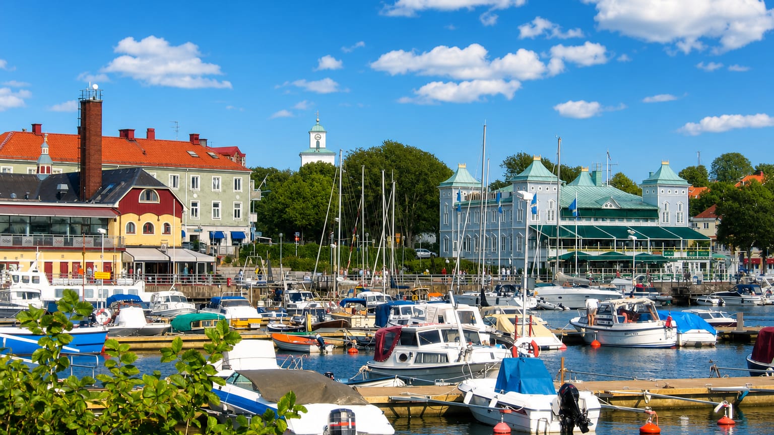 Strömstad's harbour full of boats with the green-domed spa building and old-town rooftops behind under a blue sky.