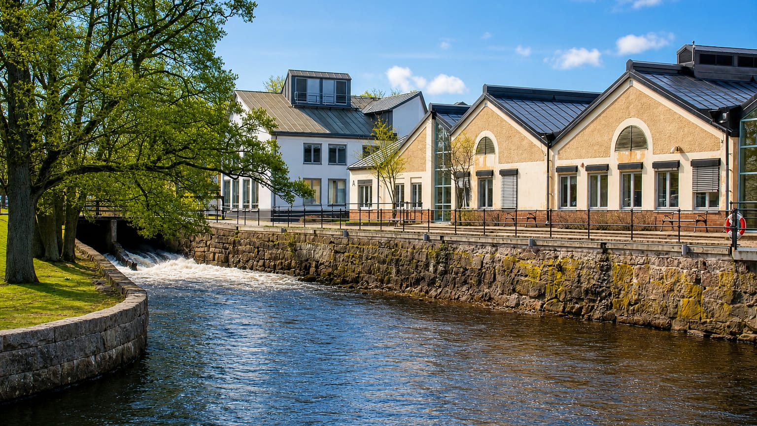 Tidaholm's old industrial mill buildings with arched windows lining the Tidan river beside a weir.