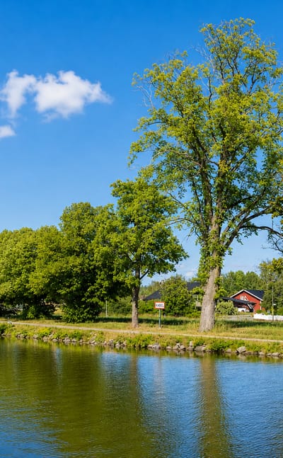 Tree-lined canal with a couple of houses on the far bank near Toreboda, Sweden