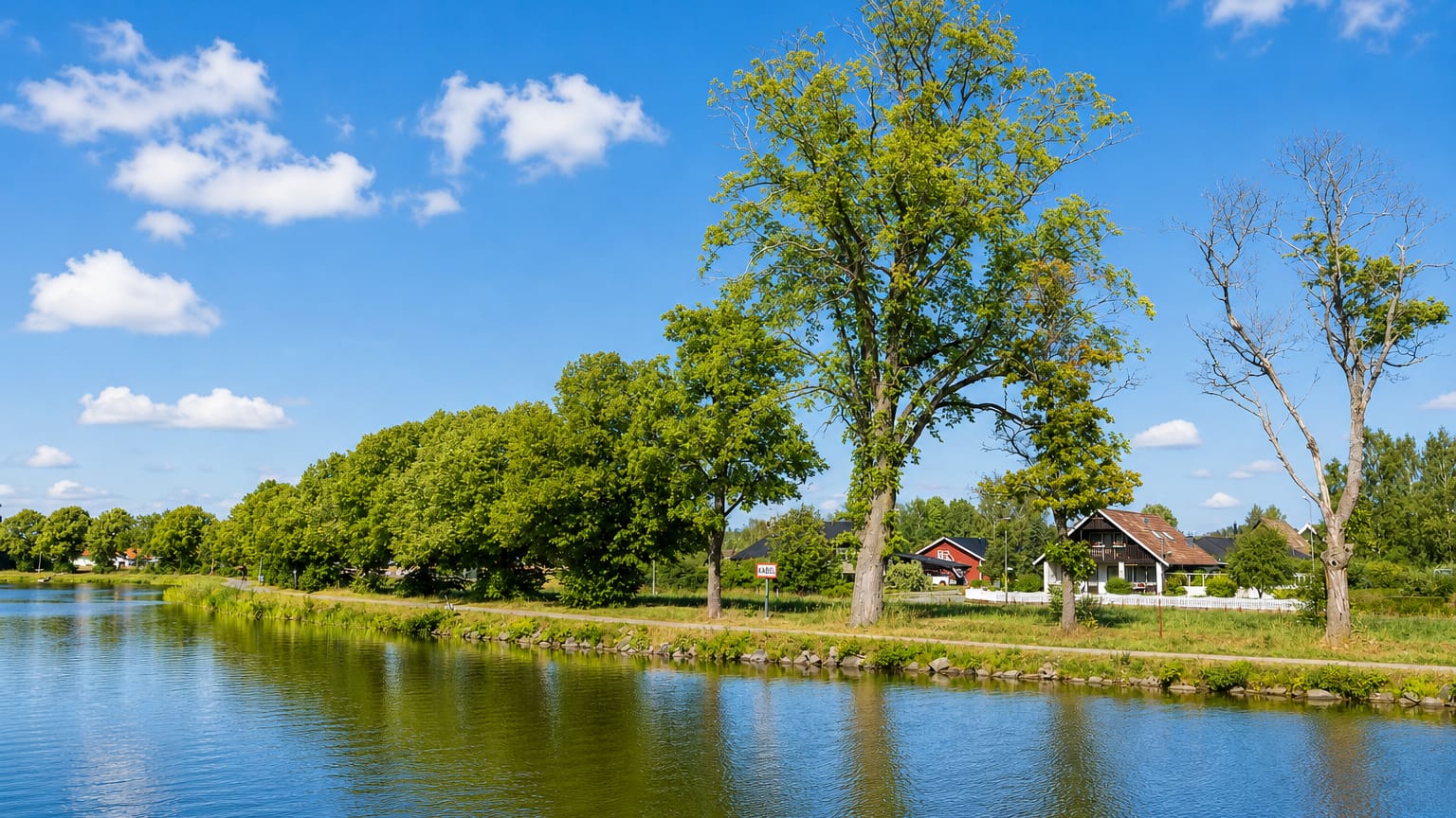 Tree-lined canal with a couple of houses on the far bank near Toreboda, Sweden
