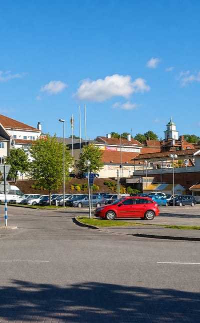 Ulricehamn town car park with parked cars, an ICA supermarket and a church cupola in the background