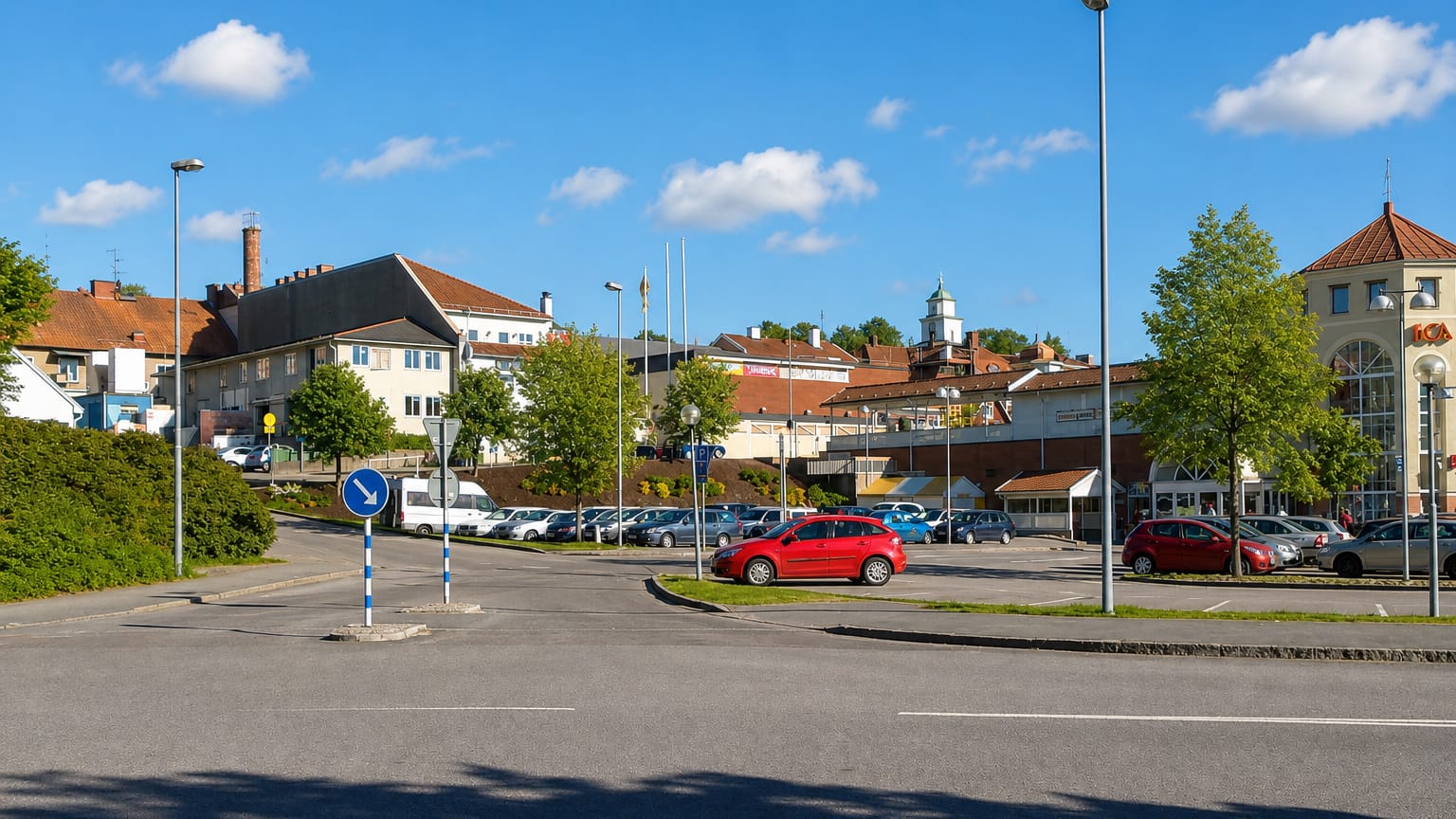 Ulricehamn town car park with parked cars, an ICA supermarket and a church cupola in the background