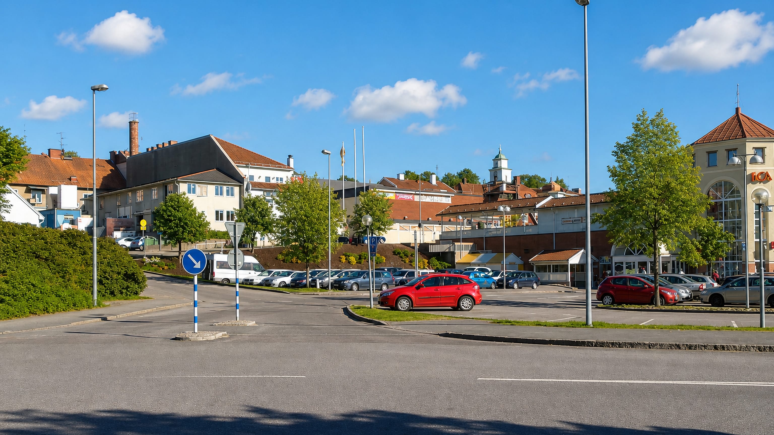 Ulricehamn town car park with parked cars, an ICA supermarket and a church cupola in the background