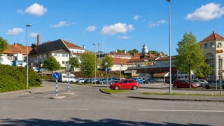 Ulricehamn town car park with parked cars, an ICA supermarket and a church cupola in the background