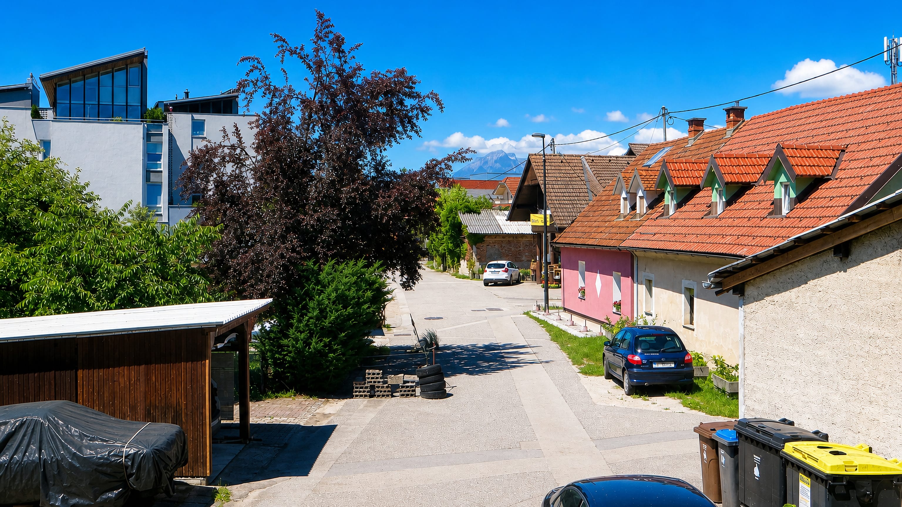 Back street of older houses and low apartment blocks with distant mountains in Dravlje, Ljubljana.