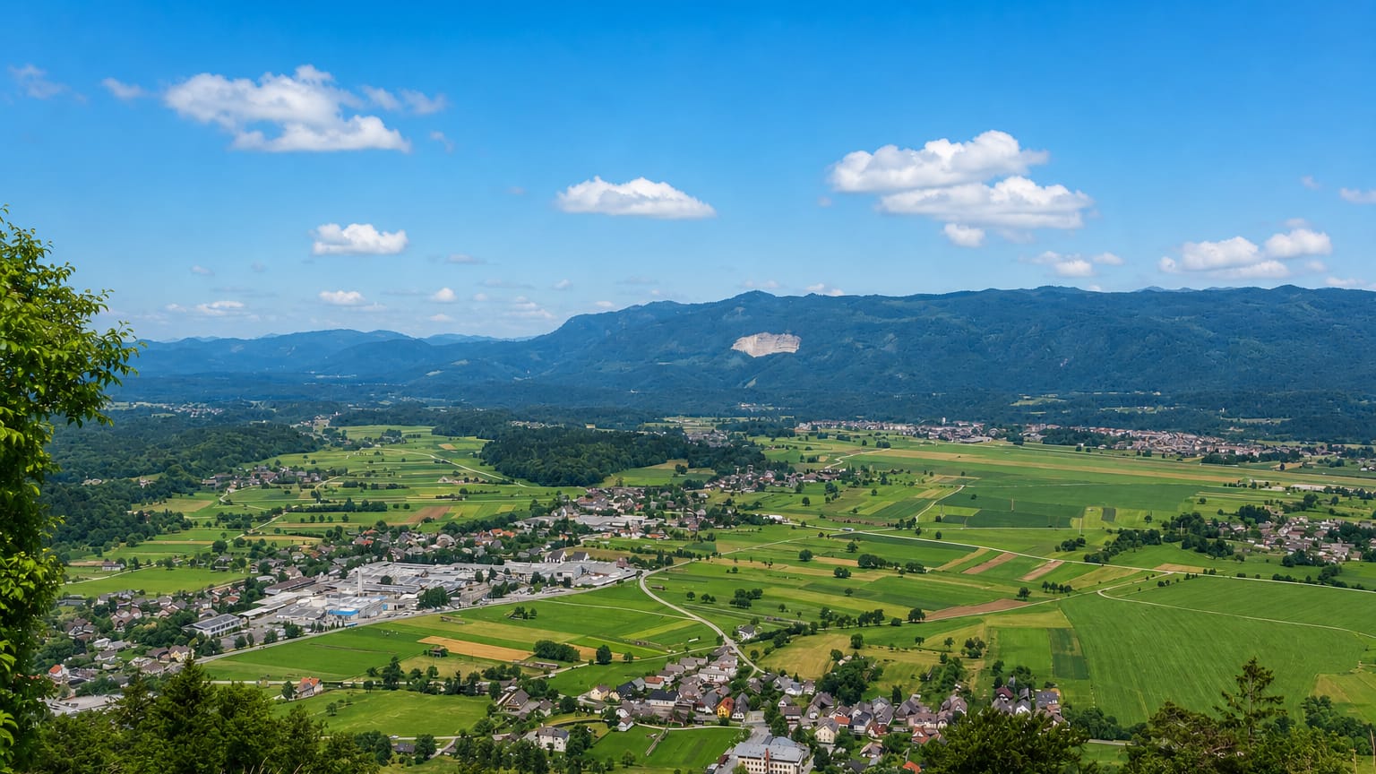 Elevated view over the rural settlement of Zapuže amid green fields with mountains on the horizon