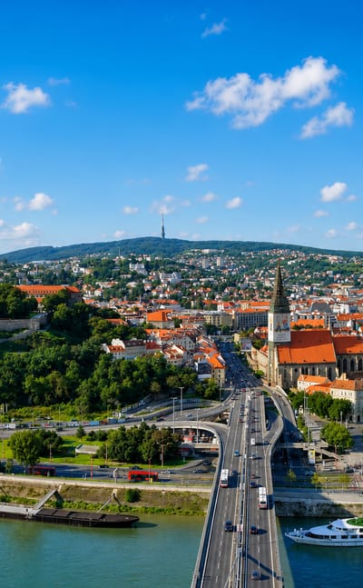 Bratislava Castle above the Old Town red roofs and St Martin's Cathedral, with the Danube and a river cruise boat