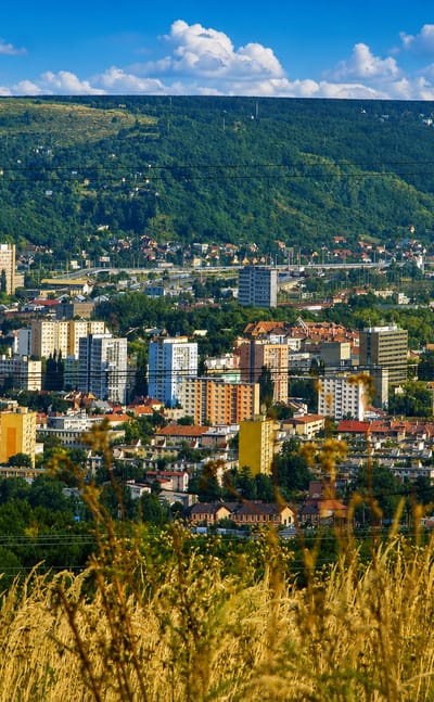Panorama of Kosice, Slovakia, with residential apartment blocks spread across a valley beneath wooded hills.