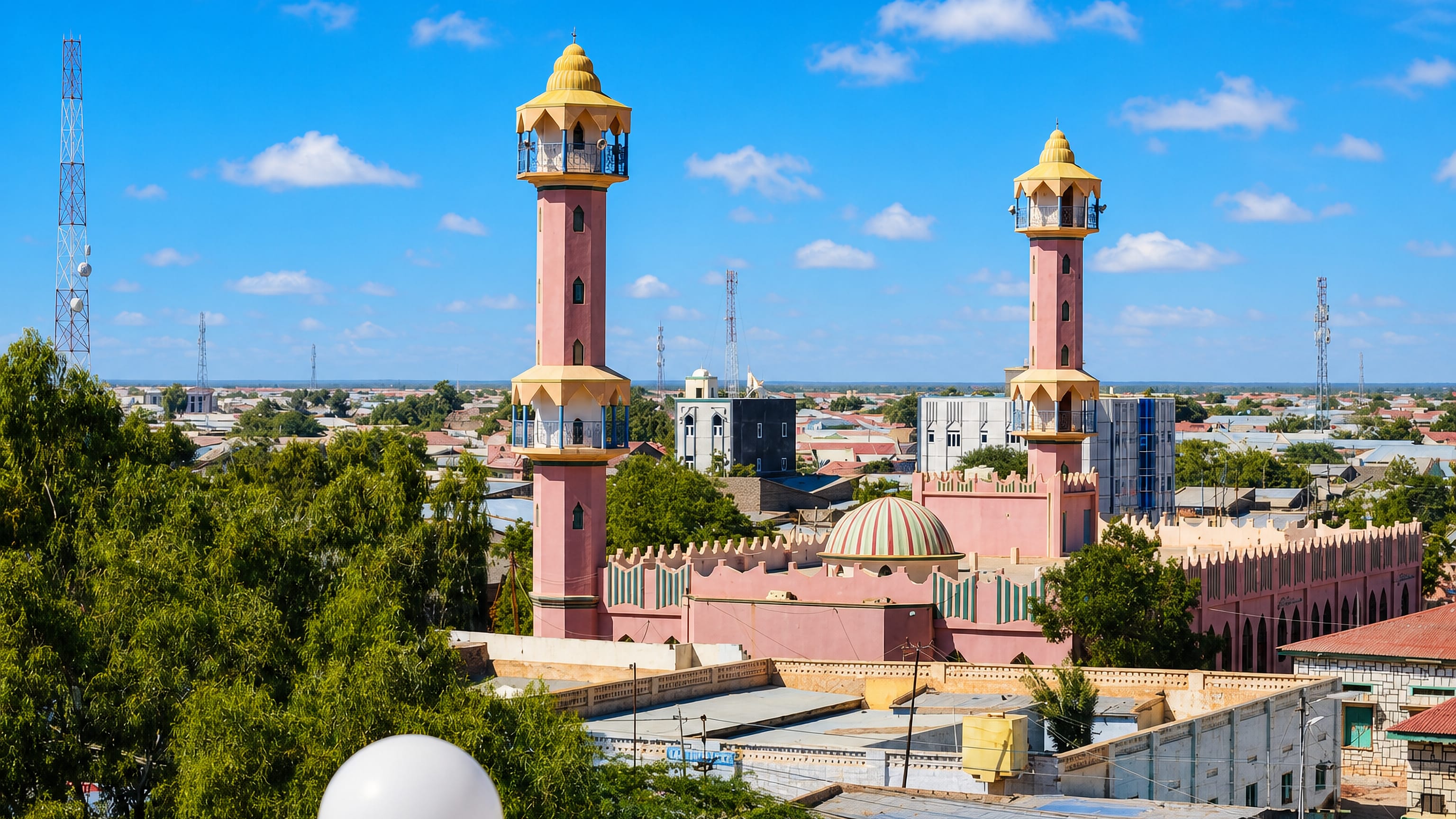 A pink twin-minaret mosque rising over the low-rise rooftops of Burao, Somalia.