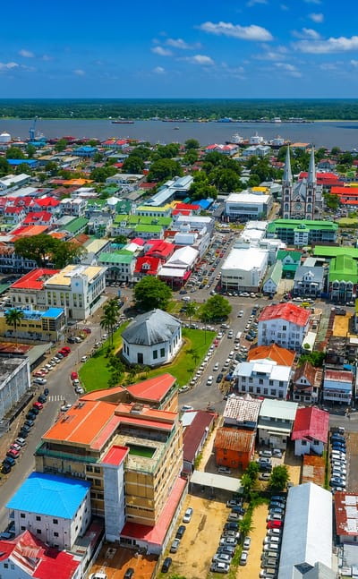 Aerial view of Paramaribo's colorful colonial rooftops and cathedral spires along the Suriname River.