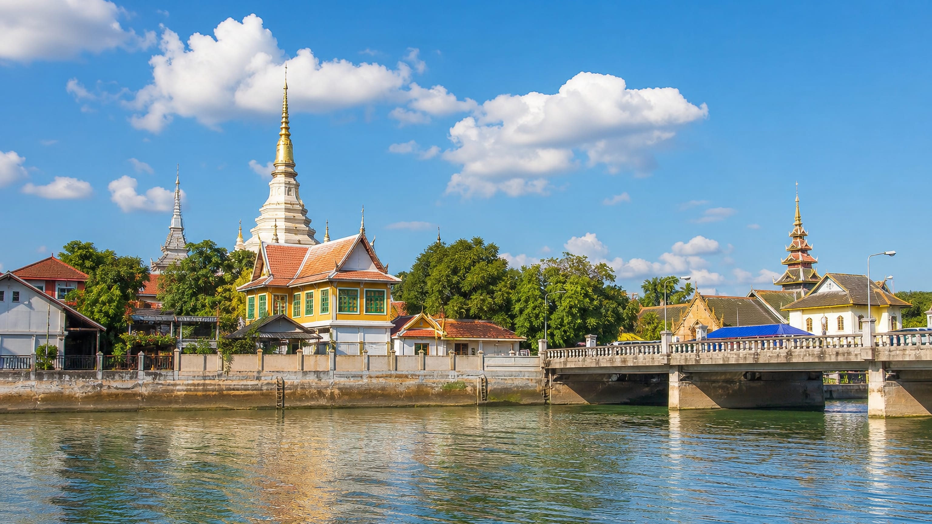 Gilded temple spires and riverside houses along the Wang River in Lampang, Thailand